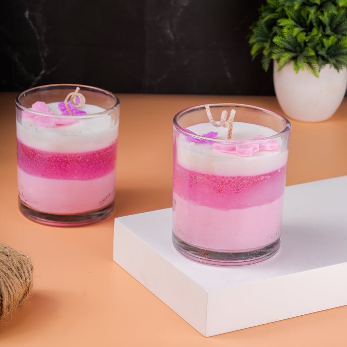 Stylish pink and white layered candles in glass jars for home decor. Perfect for adding ambiance.